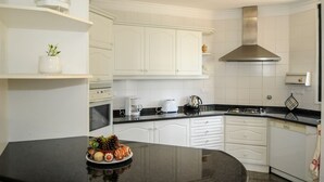 Een moderne keuken met witte kasten, een zwart aanrecht en een rvs afzuigkap.