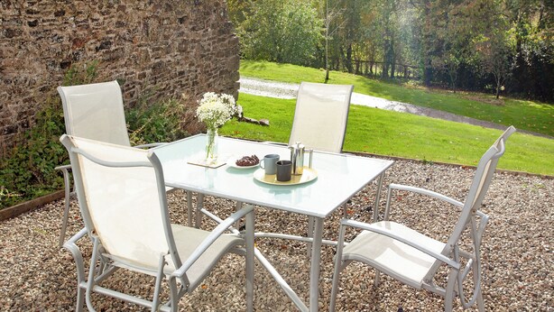 A table with chairs, a vase with flowers, and a plate with food. - UK45542-The Farm House (Sampford Courtenay, Okehampton)