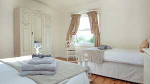 A bedroom with two beds, a wardrobe, a chair, and a window with curtains. - UK45542-The Farm House (Sampford Courtenay, Okehampton)
