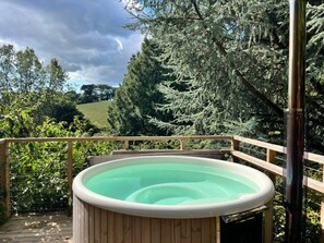 A hot tub on a wooden deck with a view of trees and a cloudy sky. - Lower Coombe Royal- Cedar Lodge with Hot Tub (Kingsbridge)