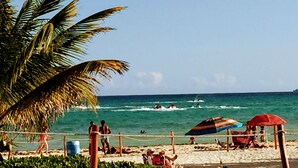A beach with palm trees, people swimming, and beach umbrellas. - Steps to Ocean Playacar Villa Private Pool hosts 25+ guest (Playa del Carmen)