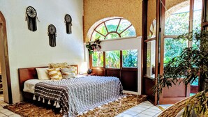 A bedroom with a bed, a large window, and a view of greenery outside. - Steps to Ocean Playacar Villa Private Pool hosts 25+ guest (Playa del Carmen)