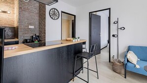 Een compacte keuken met een bakstenen muur, een moderne kookplaat en een klein barretje.