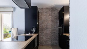 Een moderne keuken met een zwart aanrecht, een bakstenen muur en een houten vloer.