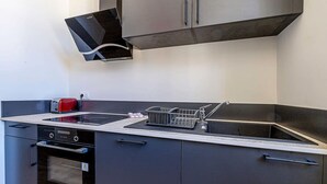 A modern kitchen with a built-in oven, a dishwasher, and a stainless steel range hood.