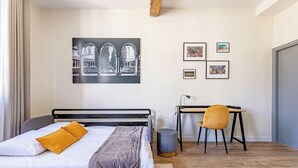 A bedroom with a bed, a desk, and a chair. There are pictures on the wall.