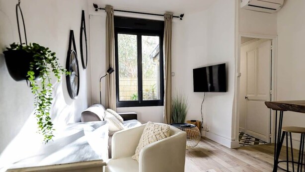 A modern living room with a sofa, a chair, a dining table, and a TV mounted on the wall. - Parga 2 · Terrasse /Clim - Capitole - Bord Garonne (Toulouse)