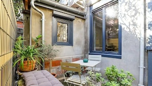 A small patio with a cushioned bench, a table, and potted plants. - Parga 2 · Terrasse /Clim - Capitole - Bord Garonne (Toulouse)