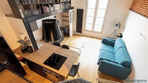 Et moderne køkken med spiseplads, en blå sofa og en reol.