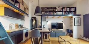 Um espaço de estar compacto com cozinha, área de refeições e um mezanino com estantes.