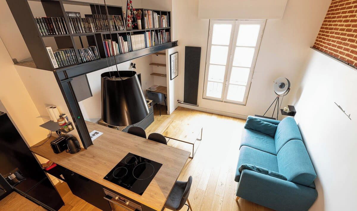 Een moderne keuken met een eethoek, een blauwe bank en een boekenkast.