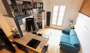 Cozinha moderna com área de jantar, um sofá azul e uma estante de livros.