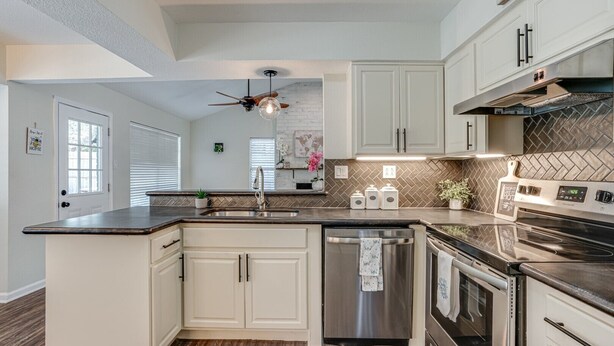 A modern kitchen with white cabinetry, a stainless steel dishwasher, a built-in oven, and a microwave. - Cute home with a Backyard pool! (San Antonio)
