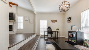 A modern living room with a fireplace, a dining area, and a workspace. - Cute home with a Backyard pool! (San Antonio)