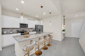 A modern kitchen with white cabinets, a granite countertop, and a central island with bar stools.