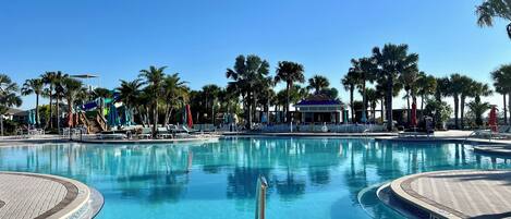 A clear blue swimming pool with a 4 ft depth marker, surrounded by palm trees and lounge chairs.