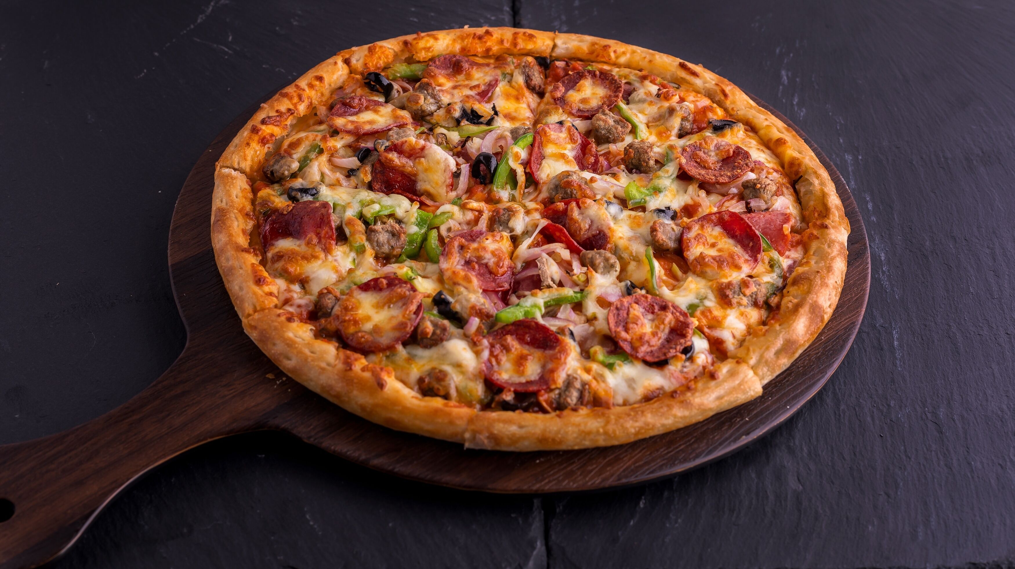 Une pizza servie sur une planche en bois.
