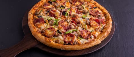 Une pizza servie sur une planche en bois.