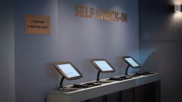 Um quiosque de auto check-in com uma placa indicando estacionamento e sala de reuniões.