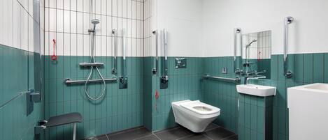 A modern bathroom with a shower, toilet, and sink, featuring teal and white tiles.