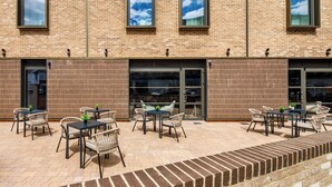 A brick building with outdoor seating and large windows. - Southgate Hotel London (London)