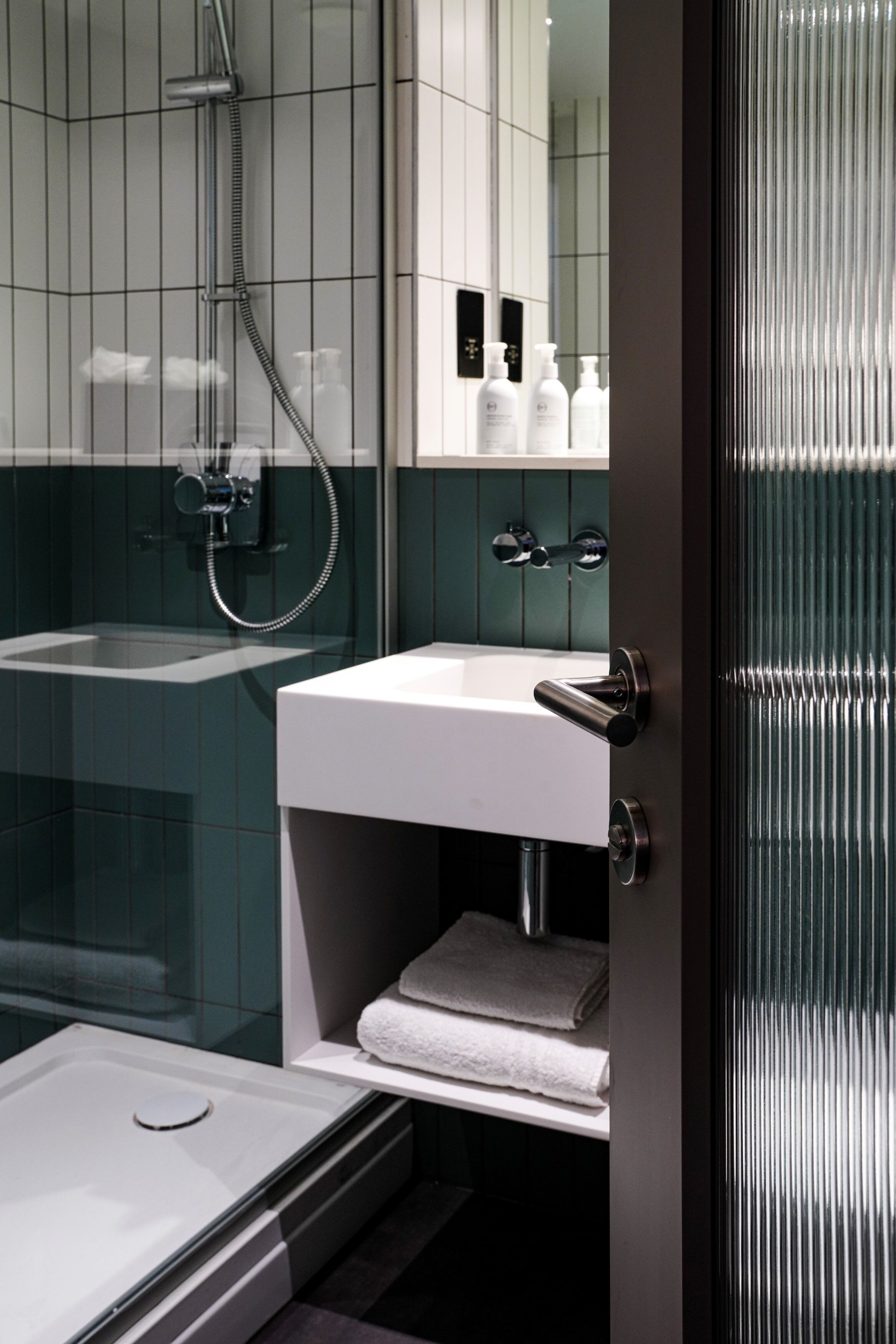 Une salle de bain moderne avec une douche à parois de verre, un lavabo blanc et un miroir au-dessus.