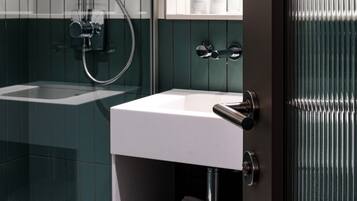 A modern bathroom with a glass-enclosed shower, a white sink, and a mirror above it.
