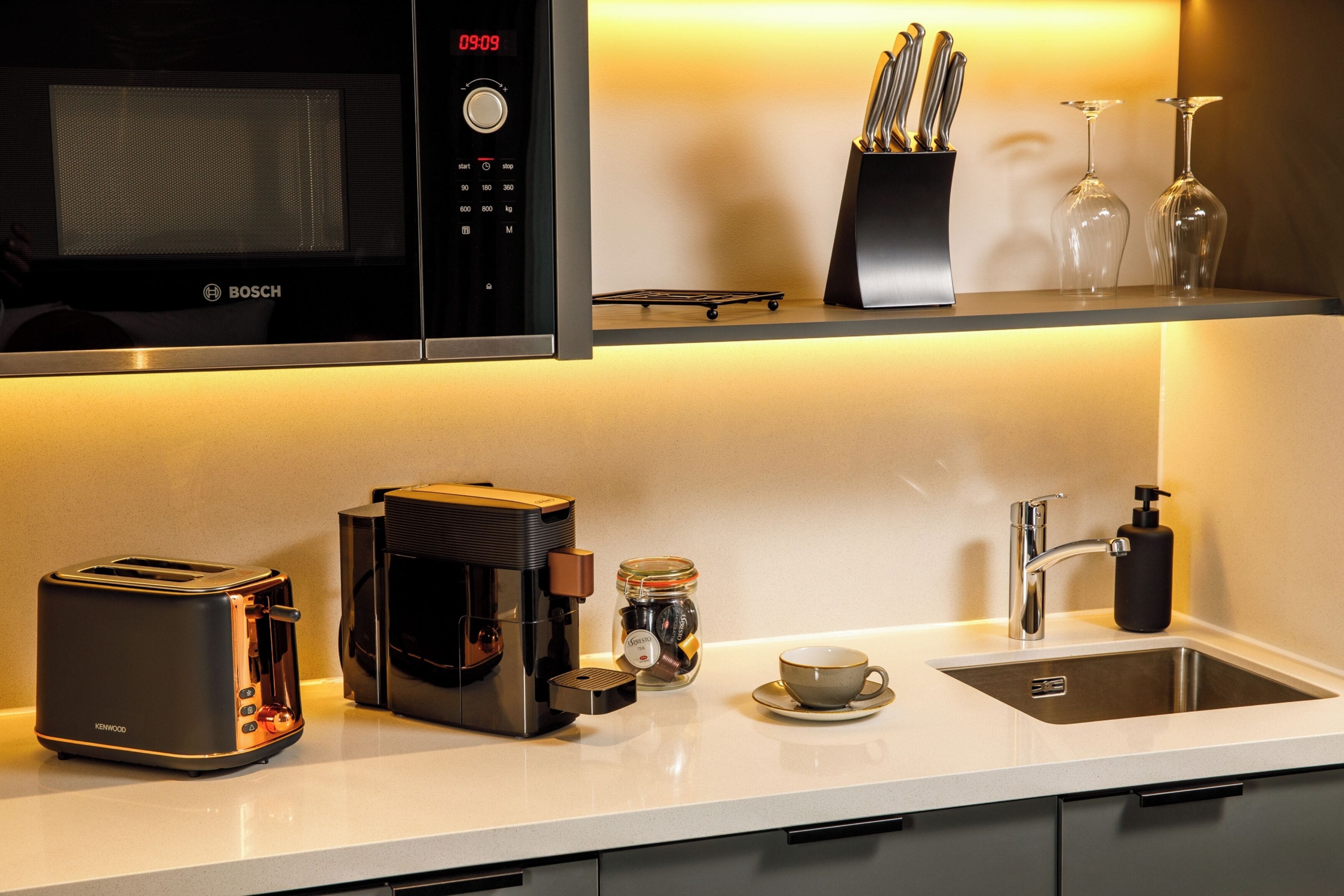 Eine moderne Küche mit einer Bosch-Mikrowelle, einer Kaffeemaschine, einem Toaster, einer Spüle und einer Tasse.