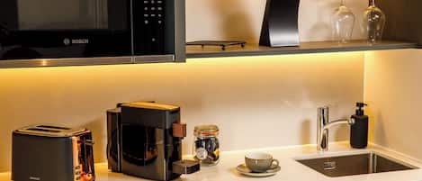 Una cocina moderna con un microondas Bosch, una cafetera, un tostador, un lavabo y una taza.