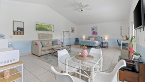 A spacious living room with a glass-top dining table, white chairs, a beige sofa, and a ceiling fan. - Michigan (Lynn Haven)