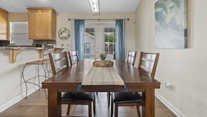 A dining area with a wooden table, chairs, and a view through glass doors to the outside. - Michigan (Lynn Haven)