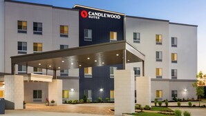 Um hotel moderno com entrada coberta, vários andares e fachada bem iluminada.