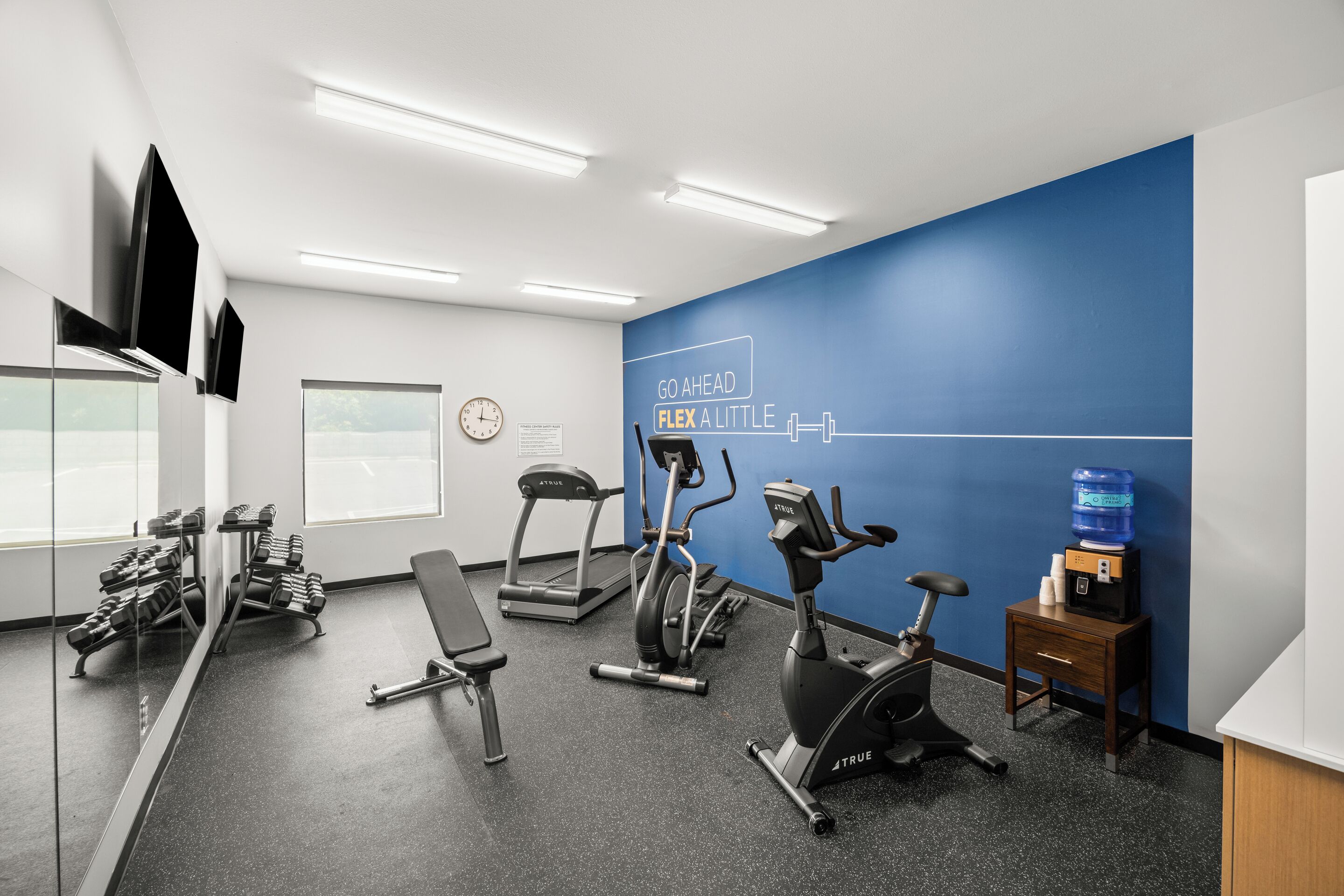 A gym with treadmills, an elliptical, and free weights.