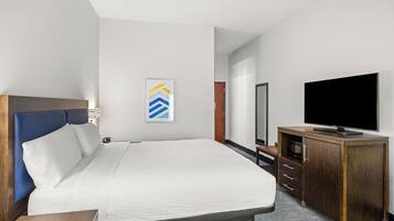 A hotel room with a bed, a TV, a wooden cabinet, and a framed picture on the wall.