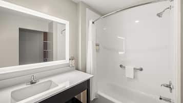 A modern bathroom with a large mirror, a sink, and a walk-in shower.