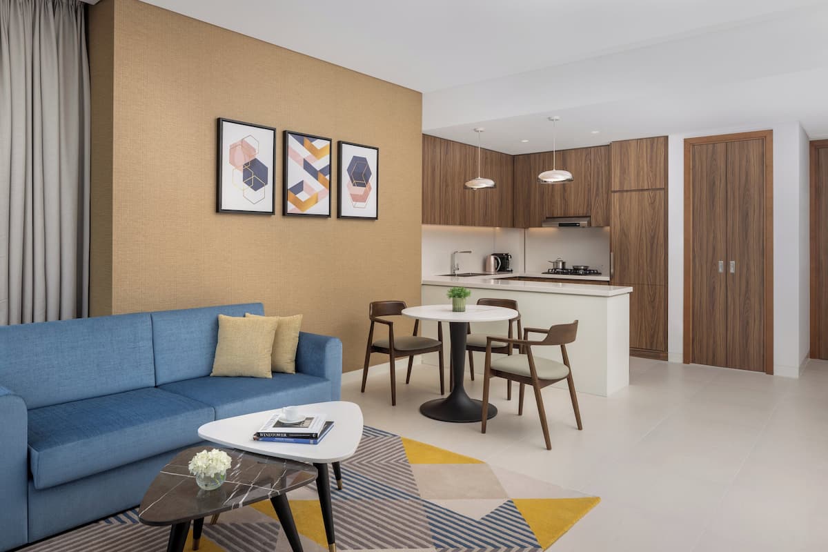 Un salon moderne avec un canapé bleu, une table basse et un coin repas comprenant un petit îlot et des chaises.