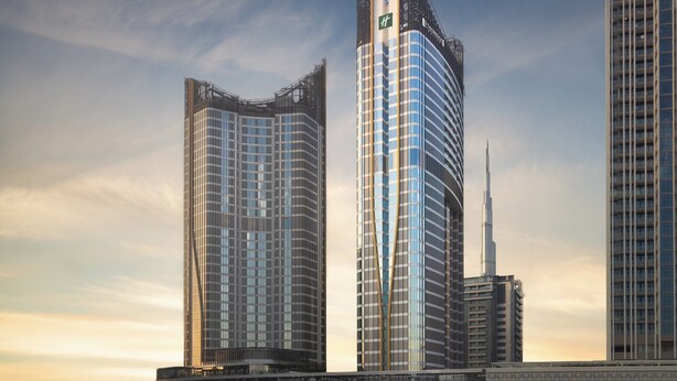Un hôtel moderne de grande hauteur, doté d’une façade incurvée originale et d’une tour imposante surmontée d’une flèche.