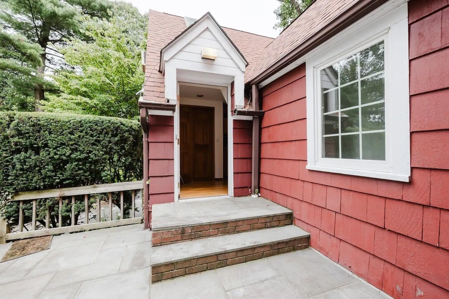 Een rood huis met een wit raam en een deur die uitkomt op een overdekte veranda.