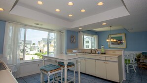 A kitchen with a large window, a sink, and a dining area with chairs. - 646 New Haven Ct (Fripp Island)