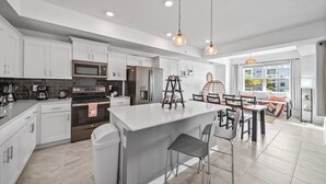 A modern kitchen with white cabinetry, stainless steel appliances, and a central island with bar stools. - 3180-207 Resort Pool View Disney Universal Orlando (Kissimmee)