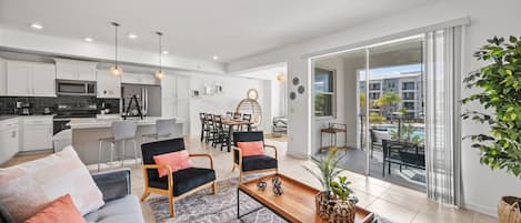 A modern kitchen with white cabinets, a microwave, and a dining area with a table and chairs.