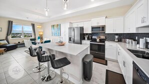 A modern kitchen with white cabinets, stainless steel appliances, and a central island with bar stools.