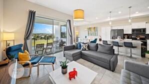 A modern living room with a grey sectional sofa, a coffee table, and a dining area with a bar.