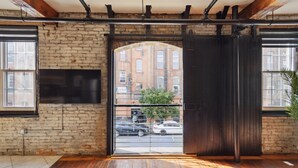 A room with a brick wall, a large wooden door, and a view of the street outside. - Chic Artist Flat on Fun Brewery & Restaurant Strip (Philadelphia)