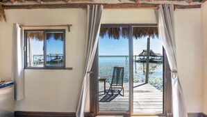 A room with a view of a wooden deck and water, a chair, and a table. - Yayum Bacalar (Bacalar)