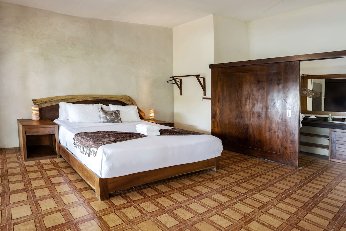 Un dormitorio con una cama de madera, una mesita de noche, un armario de madera y un espejo.