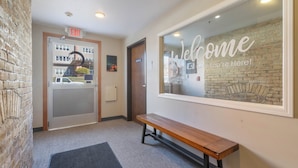 A hotel lobby with a bench, an exit door, and a welcome sign.