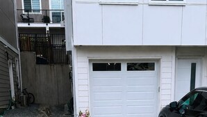 A residential garage with a designated parking area for guests, a black SUV parked inside, and a white garage door.