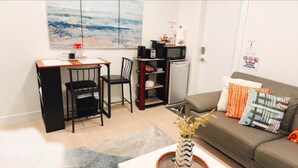 A compact living space with a kitchenette, a dining area, and a sofa with decorative pillows.