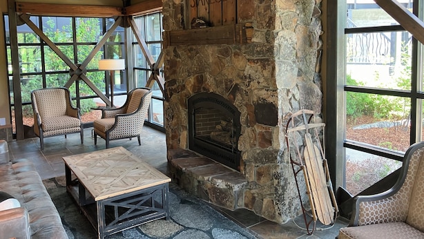 Un interior acogedor con chimenea de piedra, ventanas amplias y vigas de madera rústica.